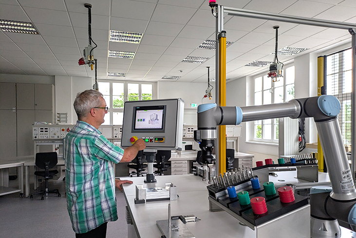 Mann im karierten Hemd arbeitet an einer Anlage zur Mensch-Roboter-Kollaboration (MRK)