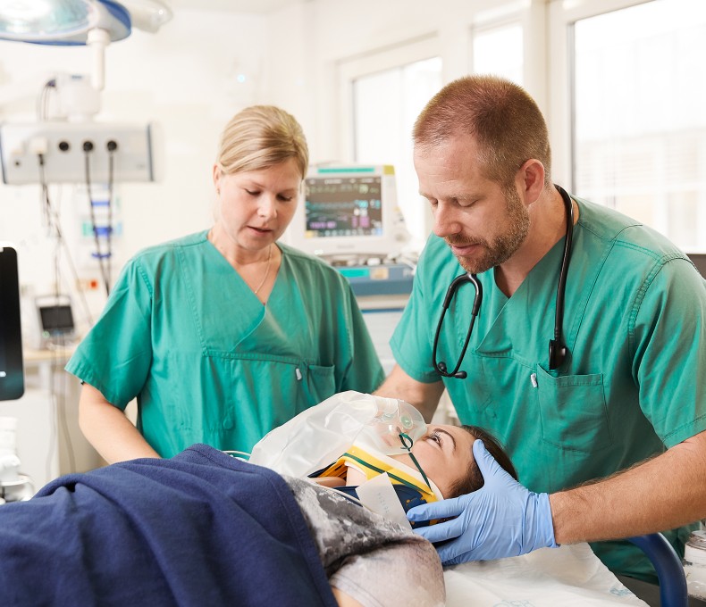 Zwei medizinische Fachkräfte versorgen eine Patientin mit Sauerstoffmaske im Krankenhaus. (Bild: BG Kliniken)